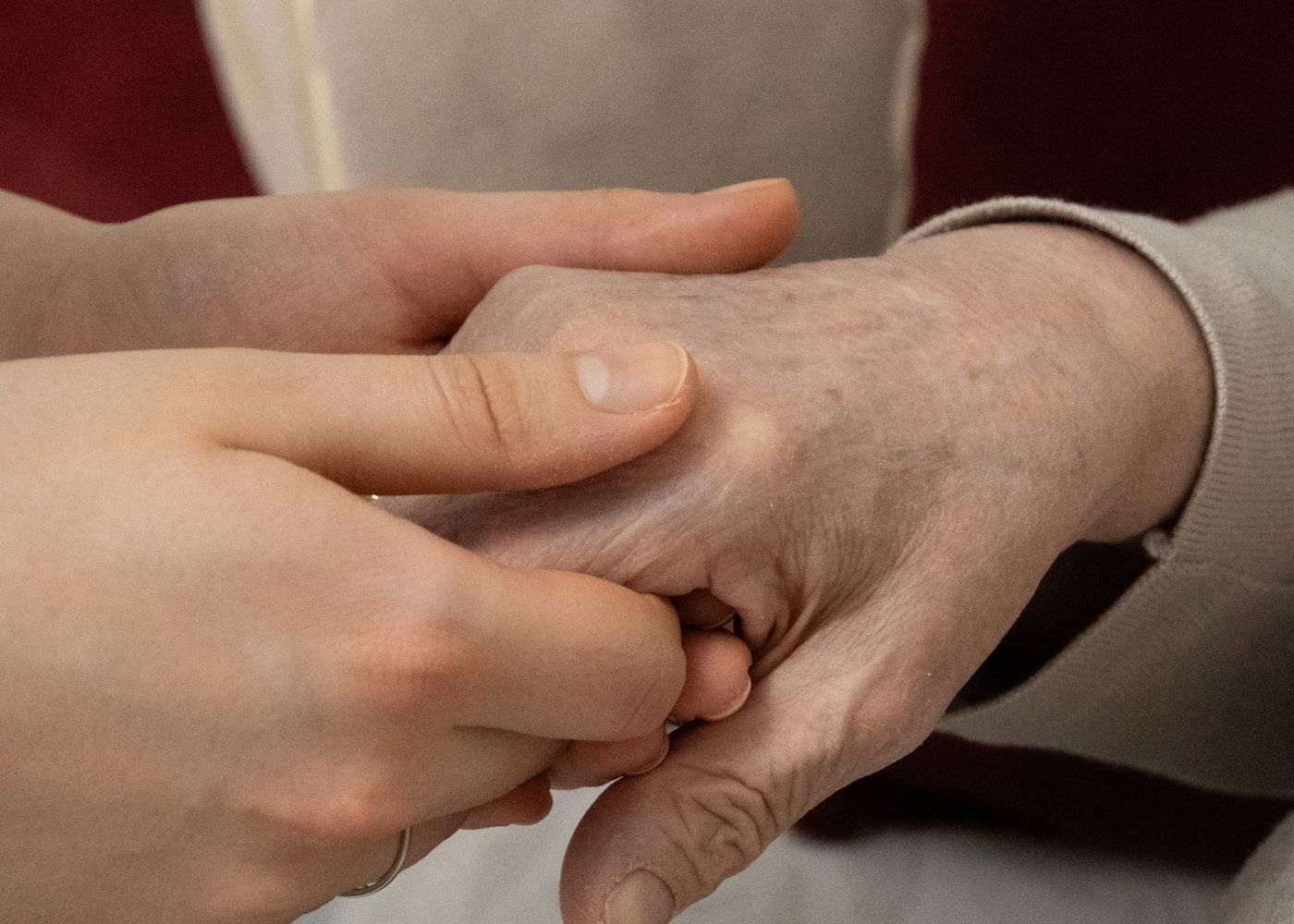 A caregiver gently holding the hand of an elderly client