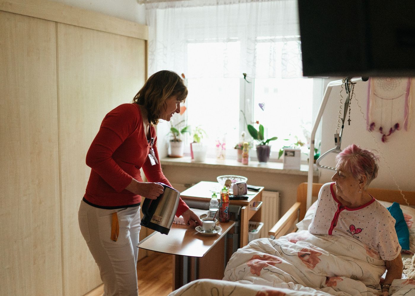 A caregiver sharing tea and conversation with an elderly woman